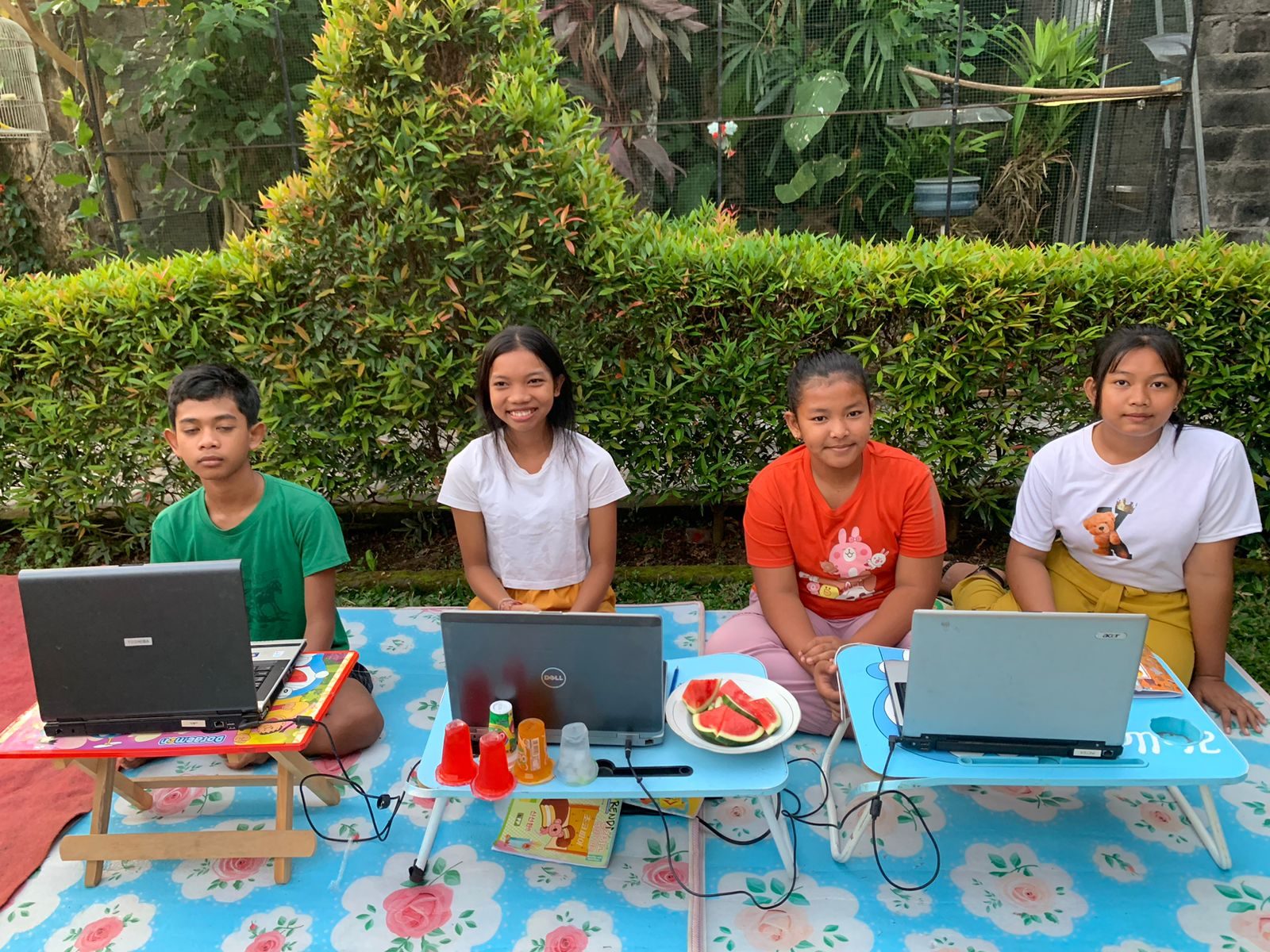 Kinderen krijgen bijles op laptops in de tuin